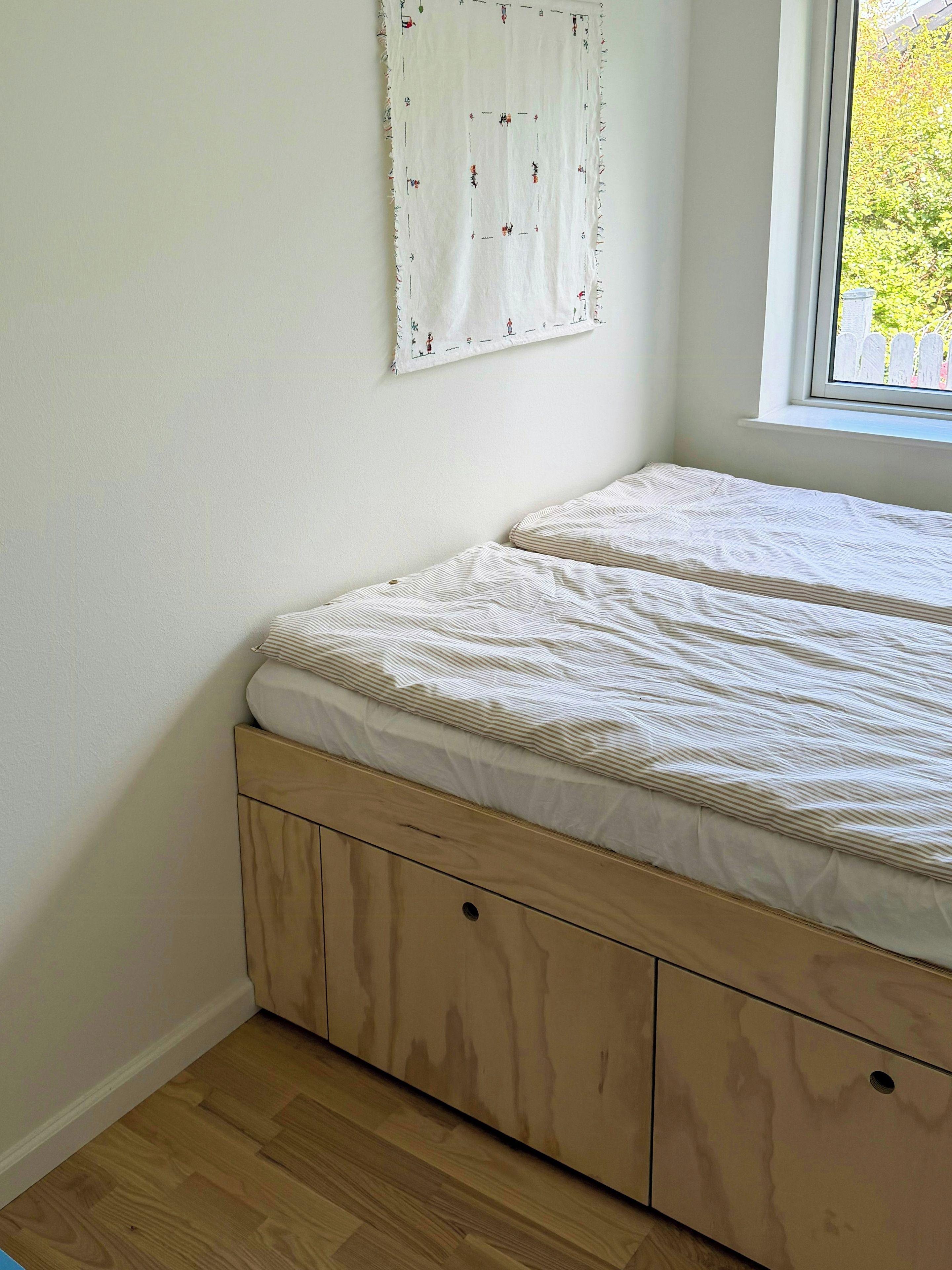 A bedroom with a bed, a window, and a wall-mounted artwork.