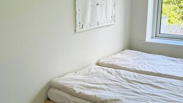 A bedroom with a bed, a window, and a wall-mounted artwork.