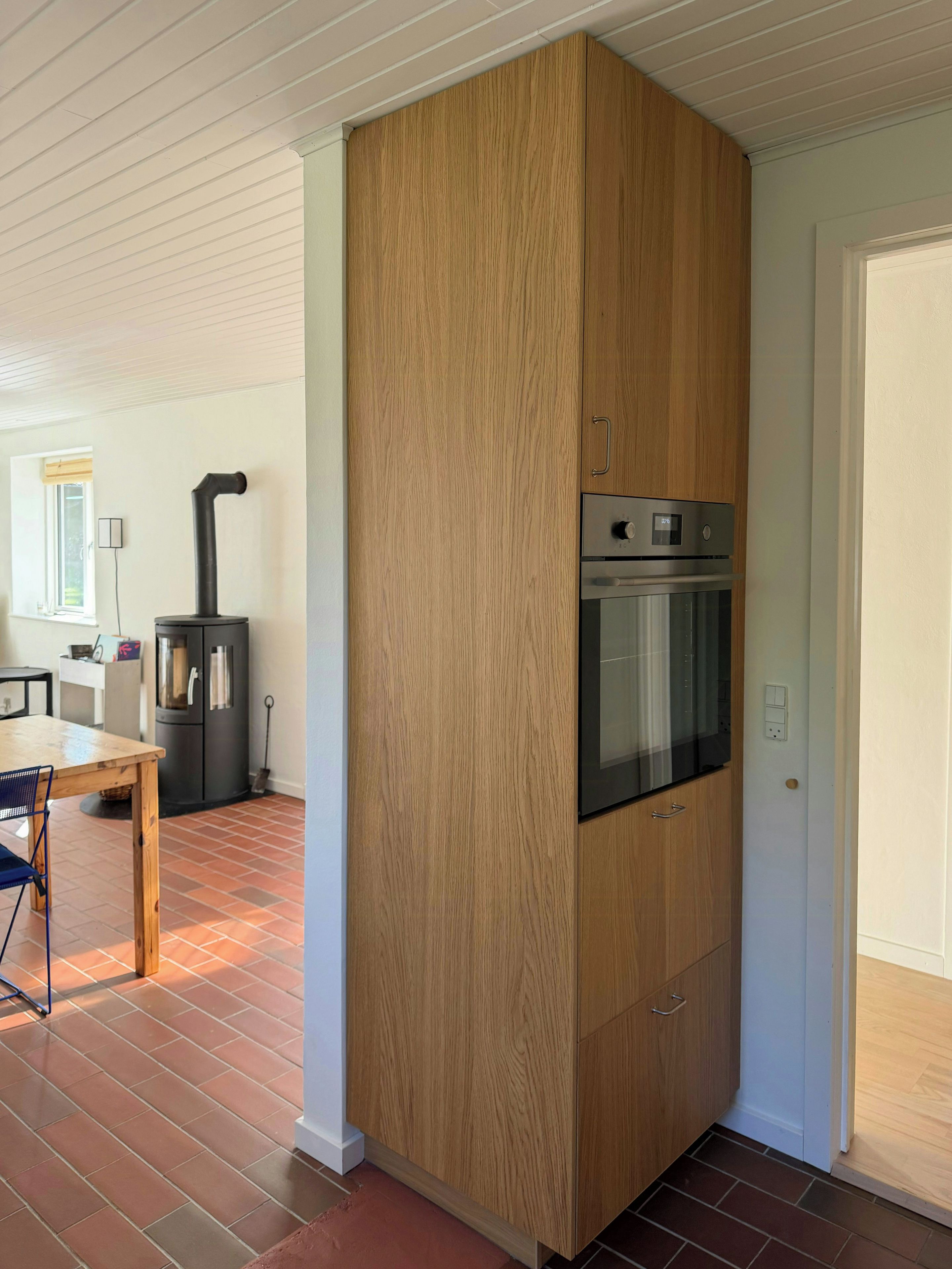 A kitchen with a built-in oven and a wood-paneled cabinet.
