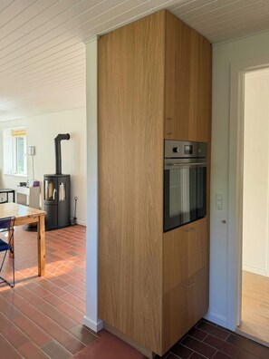 A kitchen with a built-in oven and a wood-paneled cabinet. - Renovated 1970s house by nature reserve (Vejby)