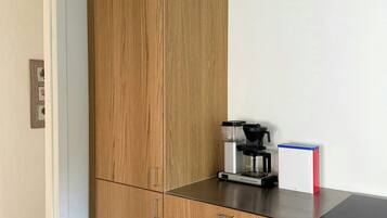 A kitchen with wooden cabinets, a coffee machine, and a red and white appliance on the counter.