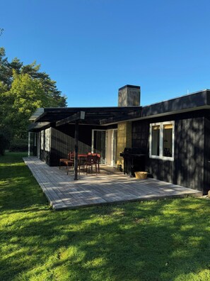 A modern house with a patio, a dining area, and a barbecue grill.