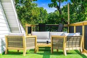 Et udendørs opholdsområde med en sofa, stole, et bord og en pergola.