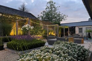 A garden patio with outdoor seating, a pergola with string lights, and a variety of plants. - Located in the heart of Adare village, 150yards from Ryder Cup Adare Manor (Adare)