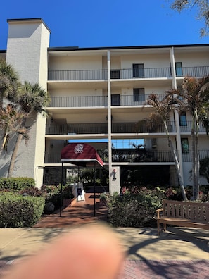 A multi-story hotel with a covered entrance, outdoor seating, and a palm tree. - Cozy 2-bedroom condo with AC in nice Siesta Key (Siesta Key)