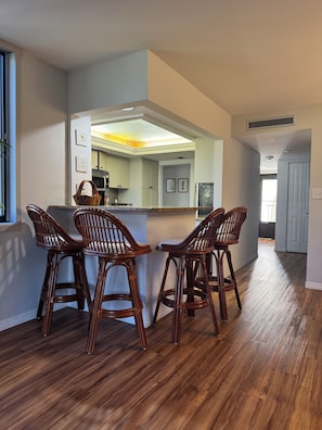 A kitchen with a central island, wooden chairs, and a view into the adjacent dining area. - Cozy 2-bedroom condo with AC in nice Siesta Key (Siesta Key)