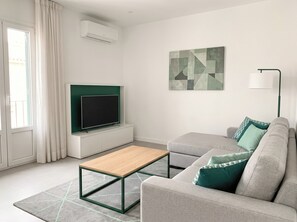A modern living room with a flat-screen TV, a sofa, a coffee table, and a painting on the wall. - The Emerald Penthouses (Portimão)