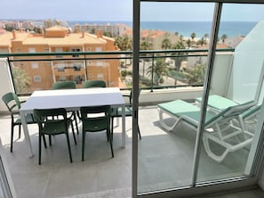 A balcony with a table and chairs, a lounge chair, and a view of the sea and buildings. - The Emerald Penthouses (Portimão)