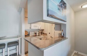 A modern kitchen with granite countertops, a microwave, and a built-in oven. - Palms Escape (Galveston)