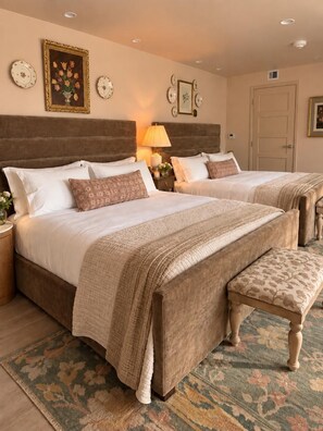 A bedroom with two beds, a nightstand, a lamp, and a patterned rug. - Hellena’s Room 304 at Keystone Hotel (Savannah)