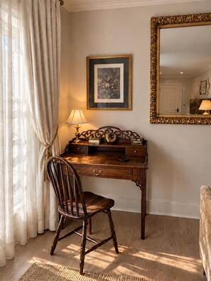 A wooden desk with a lamp, a framed picture, and a mirror with an ornate frame. - Hellena’s Room 304 at Keystone Hotel (Savannah)