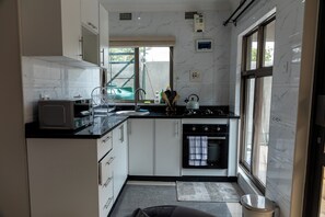Een functionele keuken met een inbouwoven, een magnetron en een gasfornuis.