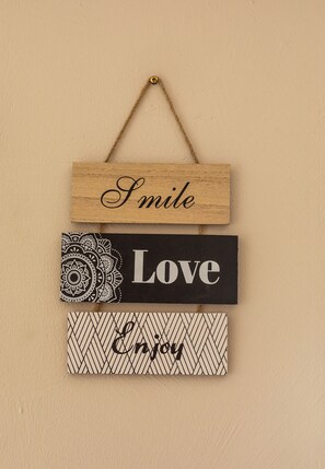 Ein Holzschild mit der Aufschrift 'Smile Love Enjoy' an einer Wand.