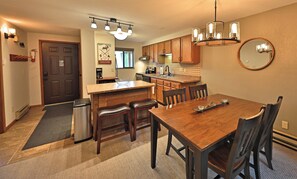 A modern kitchen with a wooden dining table, chairs, and a built-in island. - Cozy Winter Park Condo in Forest + Walk to Town! (Winter Park)