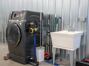 Máquina de lavar, pia e materiais de limpeza numa lavanderia.