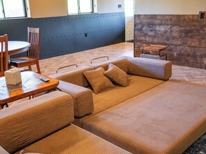 Uma sala de estar moderna com sofá seccional, mesa de centro de madeira e área de jantar com cadeira e mesa.