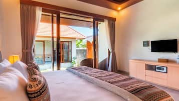 A hotel room with a bed, curtains, a television, and a view of the outside.