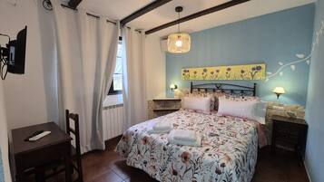 Un dormitorio con cama, escritorio, silla, ventana con cortinas, lámpara de pared y lámpara del techo.