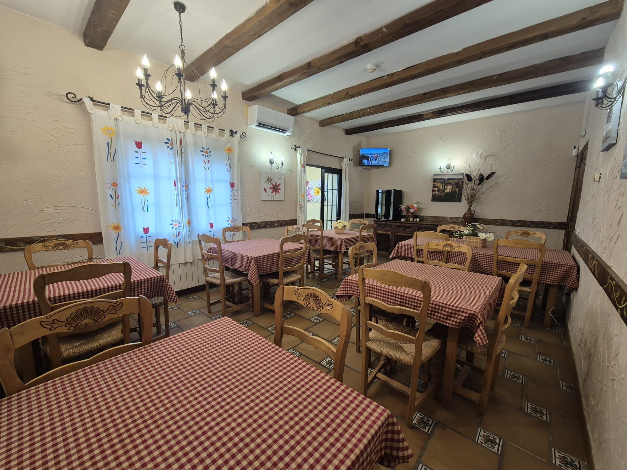Un restaurante con varias mesas cubiertas de manteles a cuadros, sillas de madera y un candelabro.