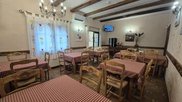 Un restaurante con varias mesas cubiertas de manteles a cuadros, sillas de madera y un candelabro.