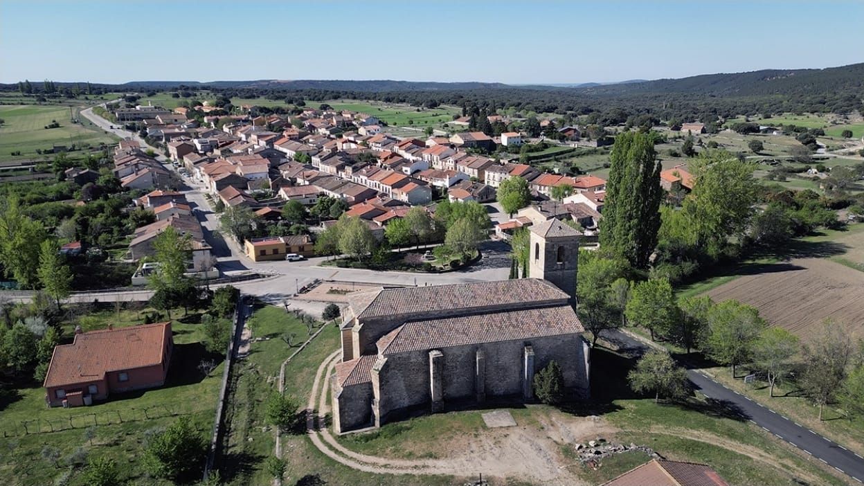 Ein ländliches Dorf mit einer zentralen Kirche, umgeben von Häusern und Feldern.