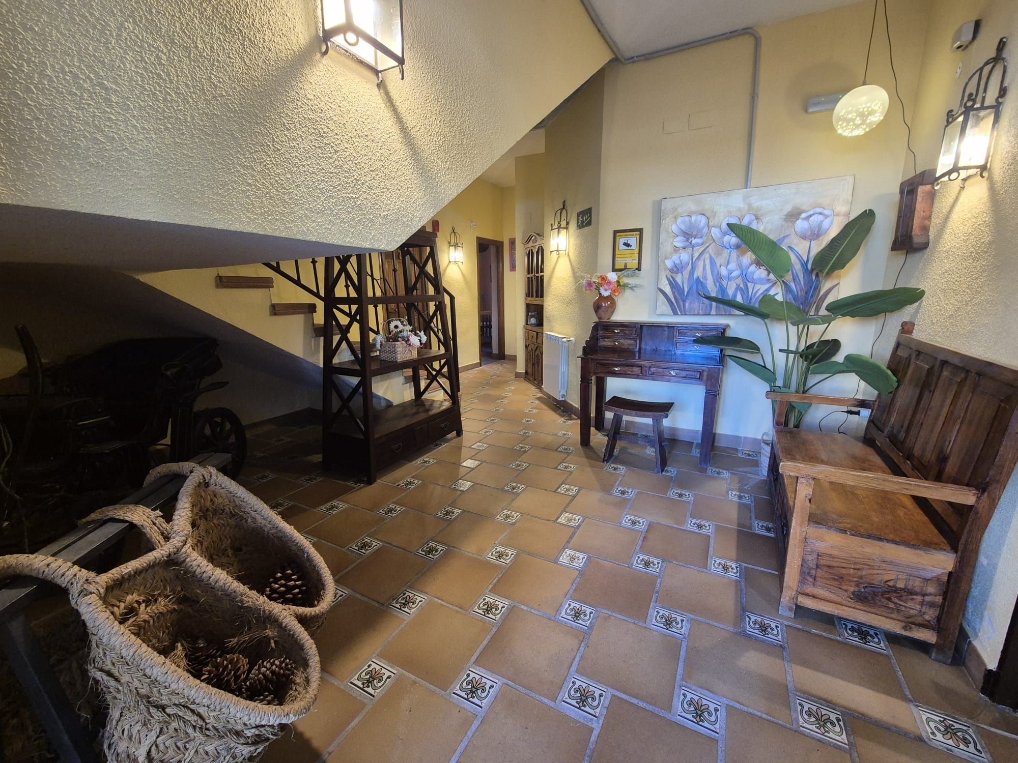 Een ruime woonkamer met een hoge nok, een trap en een eethoek met een tafel en stoelen.