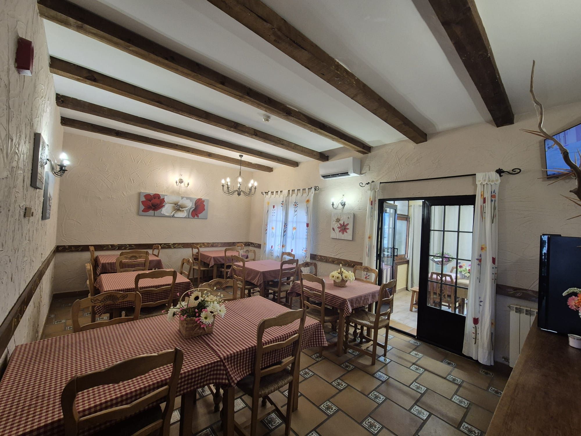 A dining area with checkered tablecloths, wooden chairs, and a chandelier.