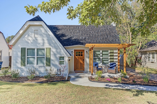 A two-story house with a front porch, a covered patio area, and a well-maintained garden.