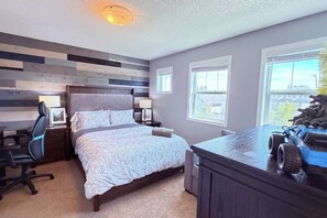 A bedroom with a bed, bedside tables, a desk, and a window. - Nolan Hill Retreat 3 BR Upper Level Home (Calgary)