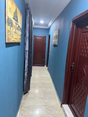Passadís amb parets blaves, terra de marbre i portes que donen a diferents habitacions.