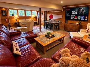A cozy living room with leather sofas, a coffee table, and a TV displaying a Netflix interface. - Wiley Inn | Peaceful 2BR Retreat in the Green Mountains (Peru)