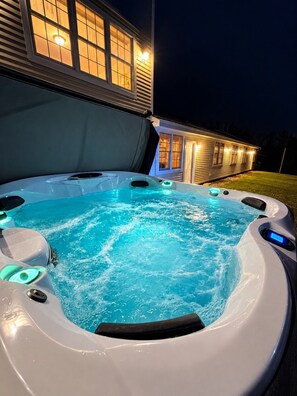 A hot tub with a digital control panel, surrounded by a house with illuminated windows at night. - The Wiley | Peaceful 2BR Retreat in the Green Mountains (Peru)