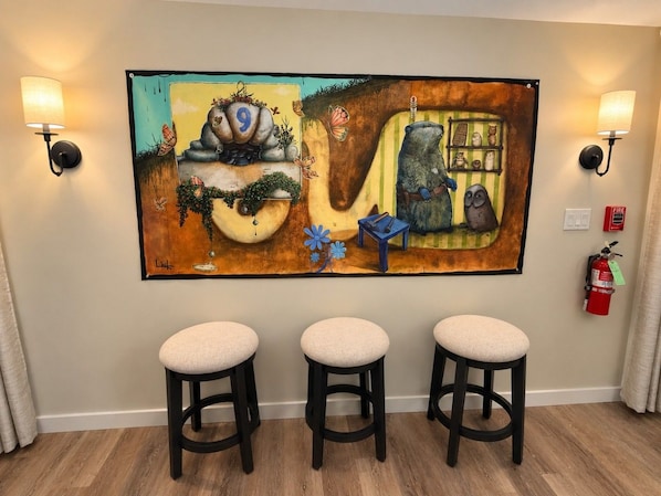 A room with a large abstract painting, three stools, and a fire extinguisher. - Wiley Inn | Peaceful 2BR Retreat in the Green Mountains (Peru)