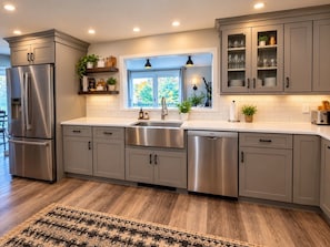 A modern kitchen with stainless steel appliances, grey cabinetry, and a large window providing natural light. - Wiley Inn | Peaceful 2BR Retreat in the Green Mountains (Peru)