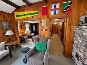 A wooden interior with a fireplace, a sofa, a table, and various flags. - Wiley Inn | Peaceful 2BR Retreat in the Green Mountains (Peru)