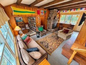 Un salon chaleureux avec un canapé, un tapis à motifs, une cheminée et une bibliothèque.