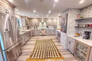 Une cuisine moderne dotée d’appareils électroménagers en acier inoxydable, de meubles de rangement en bois clair et d’un tapis à motifs.