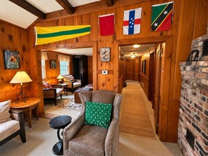 Un intérieur en bois avec un canapé, une lampe et un coin repas. Des drapeaux sont accrochés aux murs.