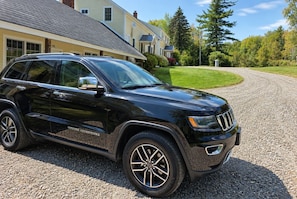 A black SUV parked on a gravel driveway in front of a residential home. - Wiley Inn | Stylish Stay in the Heart of Vermont (Peru)