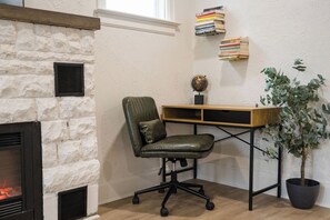 A corner office with a stone wall, a fireplace, a desk with a chair, a bookshelf, and a potted plant. - Cozy Casino Hideaway in Niagara Falls (Niagara Falls)