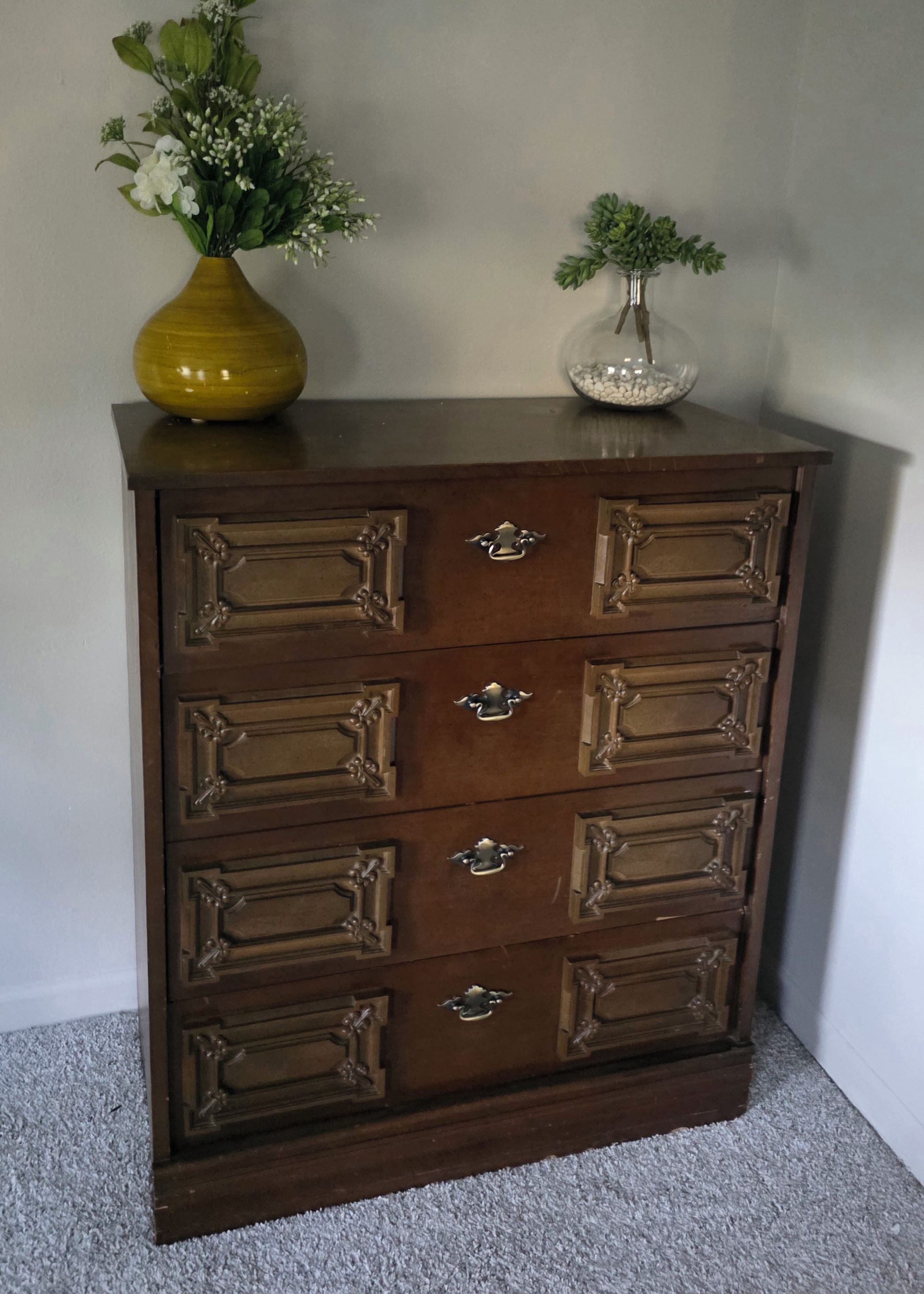 A wooden dresser with multiple drawers and ornate handles.
