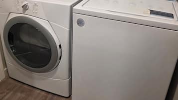 A front-loading washer and dryer unit with control panels, a registration sticker, and a label indicating a warranty or service number.