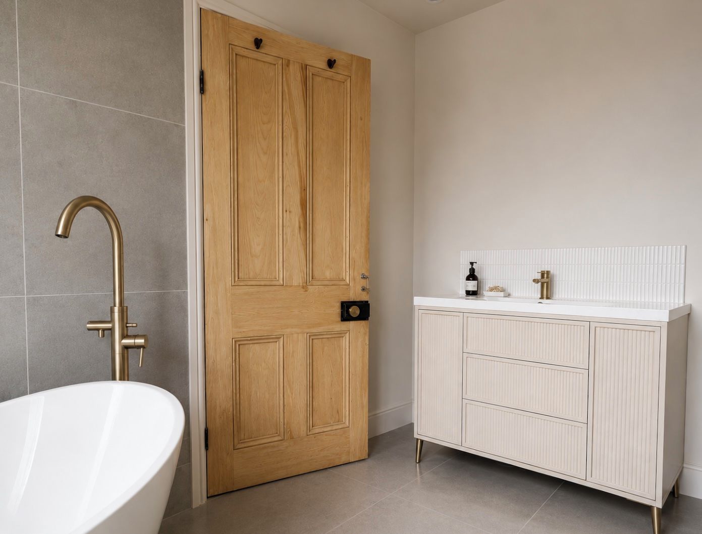 A bathroom with a freestanding bathtub, a wooden door, and a white vanity with a mirror.