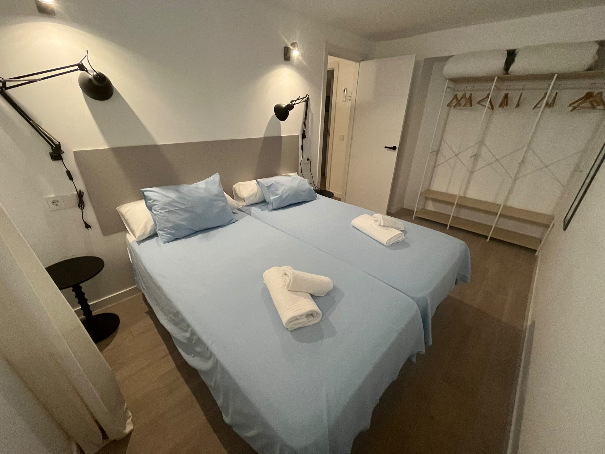 A hotel room with a bed, two bedside tables, a desk, and a wardrobe.