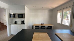 A modern kitchen with built-in appliances, a dining area with a table and chairs, and a window with a view. - Grandparents' House (Torremolinos)