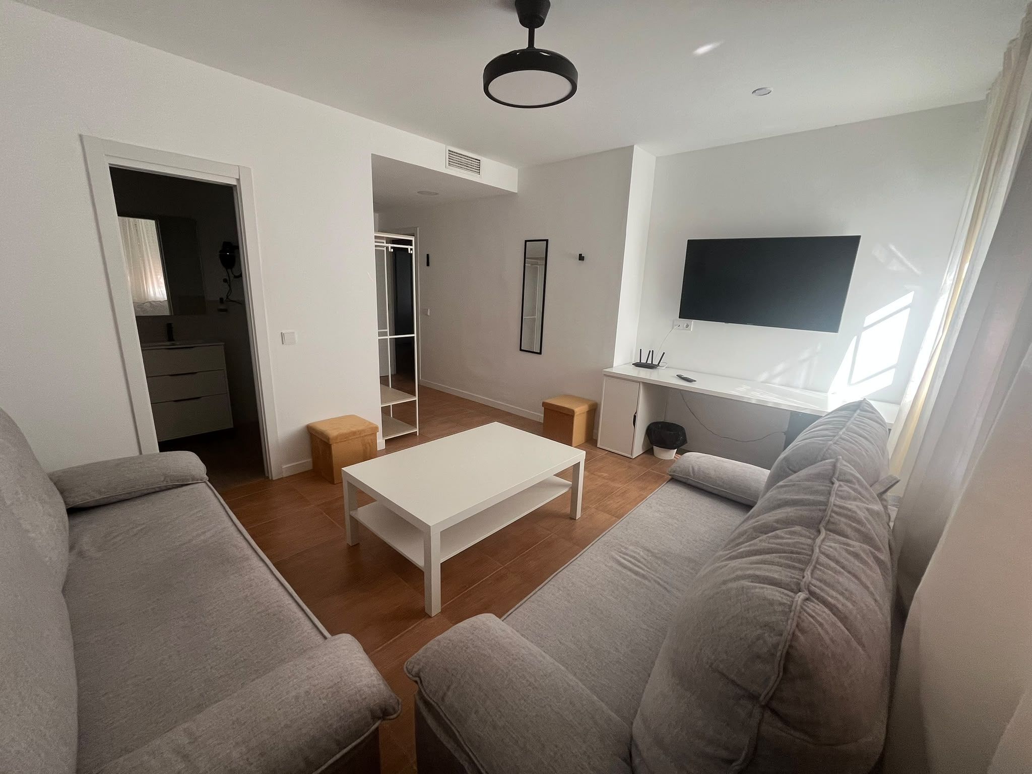 A modern living room with a white sofa, a coffee table, and a TV on the wall.