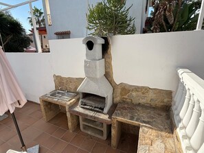 An outdoor stone-built wood-fired oven with a chimney, a sink, and a bench. - Grandparents' House (Torremolinos)