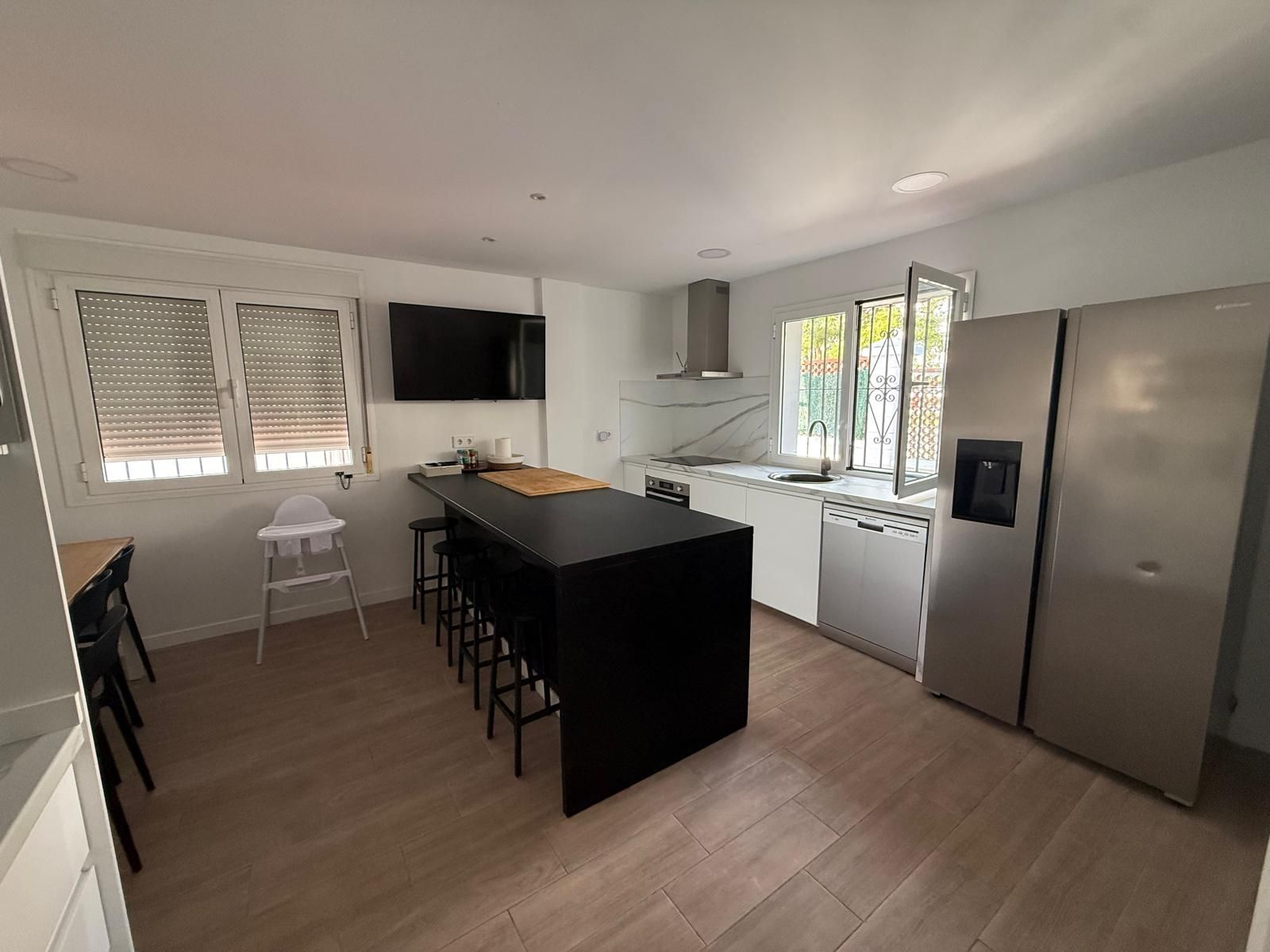 A modern kitchen with a central island, a built-in dishwasher, and a large refrigerator.