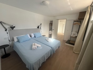 A hotel room with two beds, a desk, a chair, a mirror, and a wardrobe. - Grandparents' House (Torremolinos)