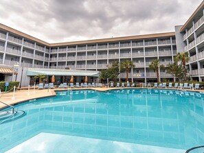 A hotel with a large outdoor pool, multiple balconies, and a covered seating area. - 2-bedroom Condo - Ocean View with Beach Access (Hilton Head Island)